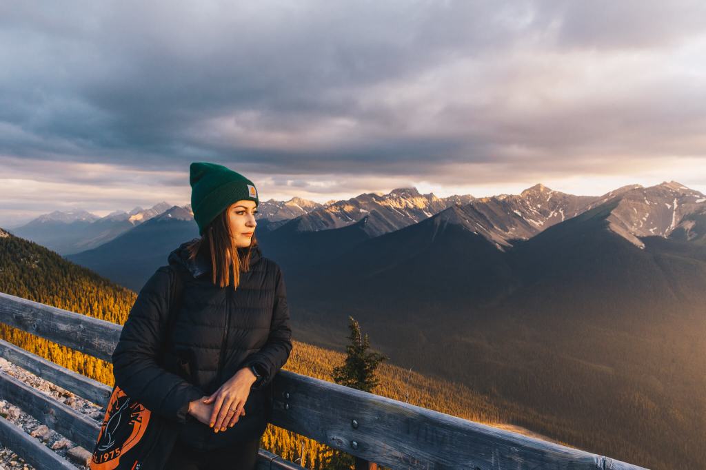 woman posing at the top of sulphur mountain at sunset with mountains in the background